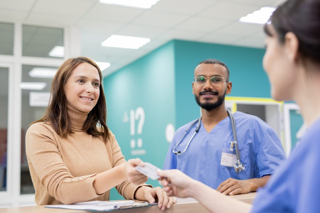 Patient giving credit card to receptionist in clinics to pay for medical service