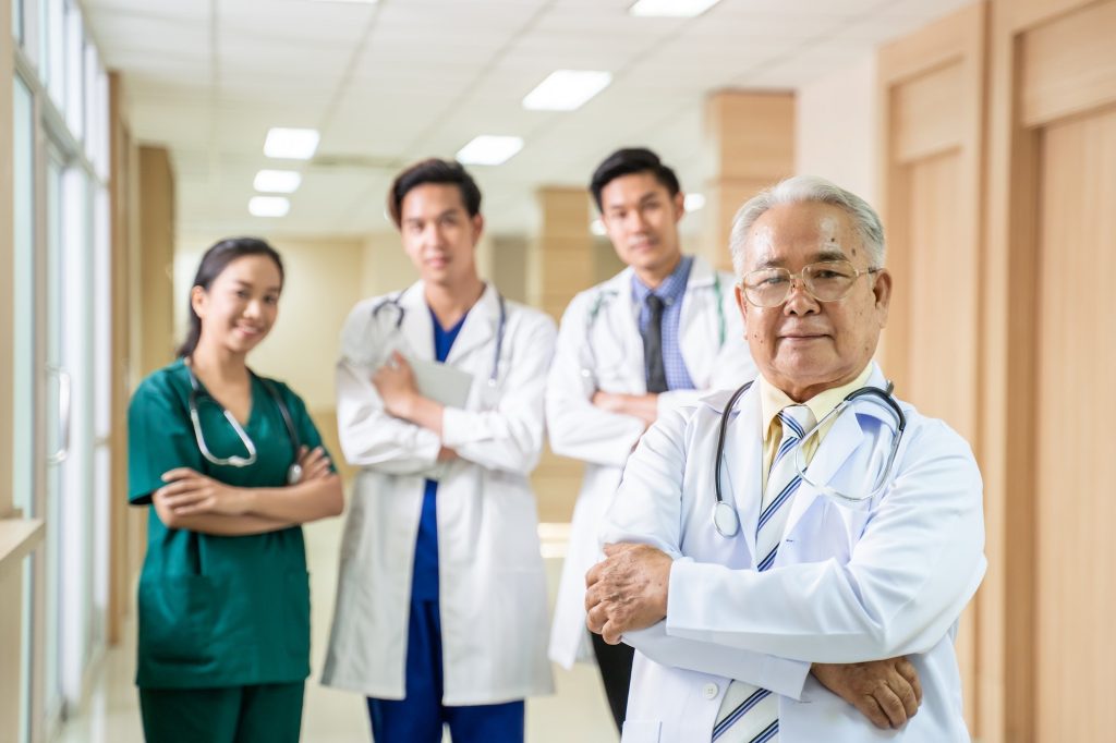 Portrait of professional variety of medic team group standing crossing arms in hospital.